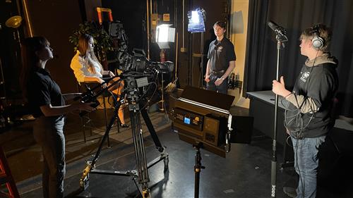 Studio set #2 talent prepares surounded by crew and thematic lighting