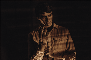 Color Noir photo of boy putting on a glove