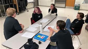 Production team at table discuss story ideas